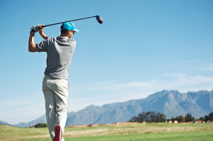 Golfer hitting tee shot with driver from teebox, on beautiful co